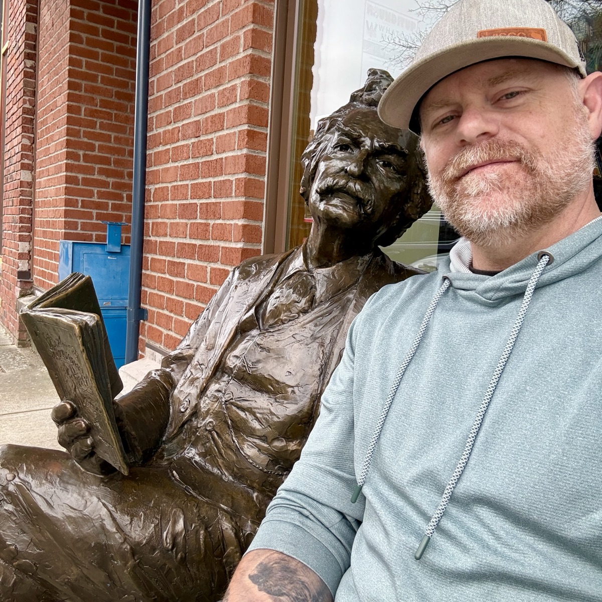 Derek with a bronze statue of a man reading
